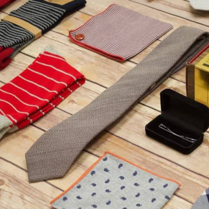 Close up of a tie, two pocket squares, and socks on a wooden table